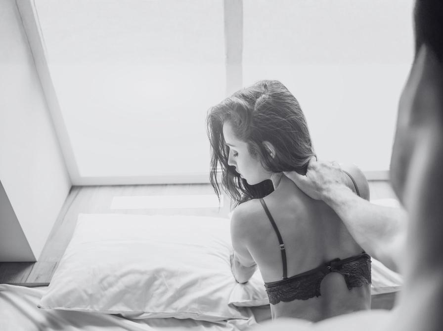 Foto af kvinde på seng med en mands hånd på skulderen